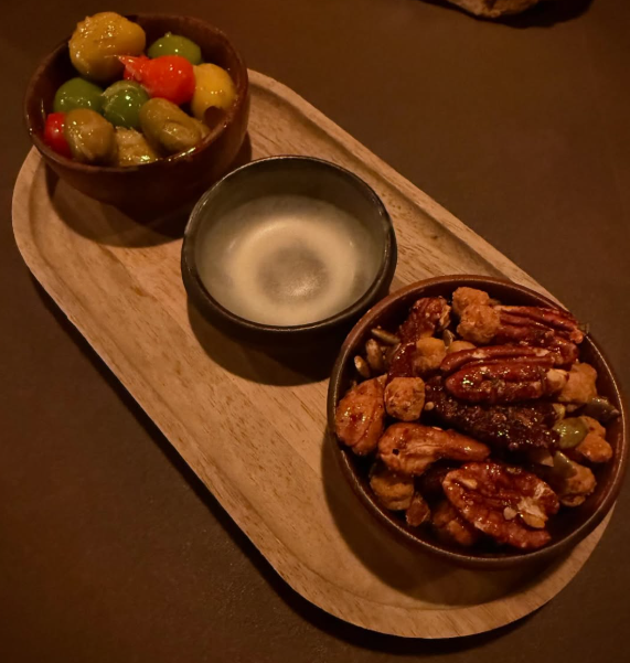 a snack platter with glazed nuts and colorful olives